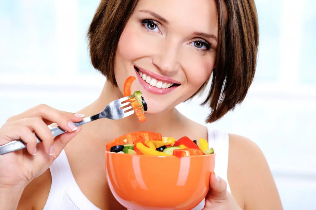 woman with a plate of  vegetable salad in hands